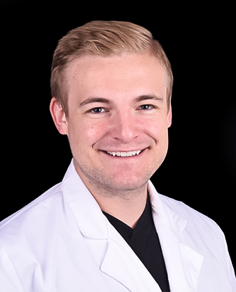 Dr. Lysak wears a white lab coat over a black shirt, standing against a black background that creates strong visual contrast. The clean and professional appearance suggests a medical or scientific context, ideal for healthcare or academic branding.